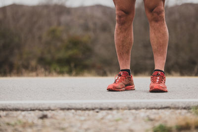 Low section of man standing on road