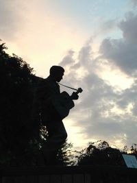 Low angle view of photographer photographing against sky