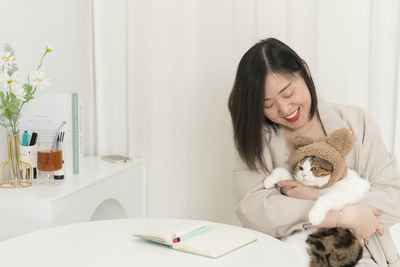 Asian business and writer woman smile and happy during play with her cat during work at home