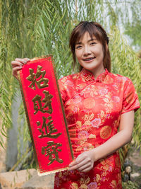 Smiling young woman standing against red wall