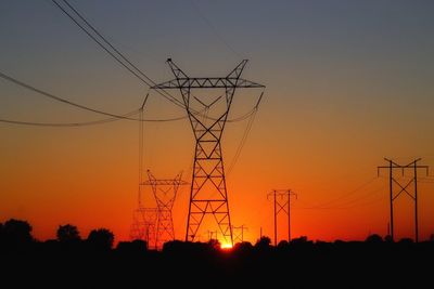 Low angle view of silhouette electricity pylon against sky during sunset