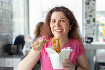 Portrait of smiling woman eating noodles
