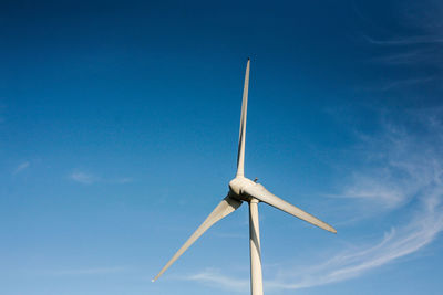 Low angle view of windmill against blue sky