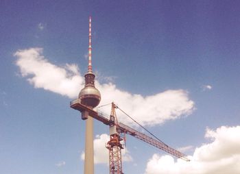 Low angle view of crane by fernsehturm against sky