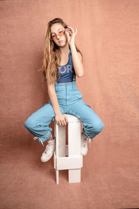 Portrait of a smiling young woman sitting against wall