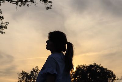 Low angle view of teenage girl standing against sky
