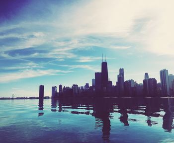 City at waterfront against cloudy sky