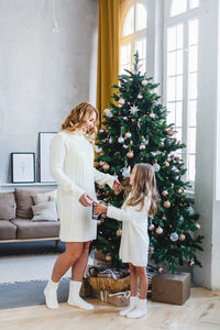 Woman standing by christmas tree at home