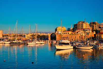 Sailboats moored in harbor against clear blue sky