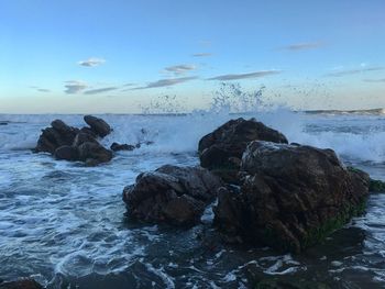 Rock formation on beach against sky