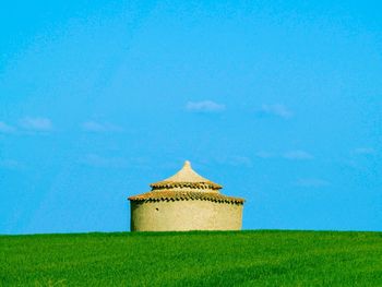 Building on field against blue sky