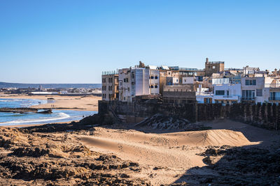 City skyline with rock formations at beach in sunny day against blue sky