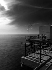 Pier on sea against cloudy sky