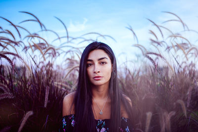 Portrait of beautiful young woman against sky on field