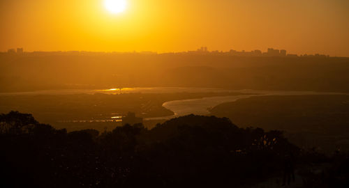 Scenic view of silhouette landscape against orange sky