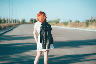 Rear view of woman with umbrella walking on road