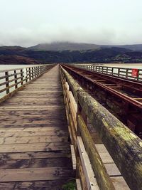 Wooden bridge over mountain against sky