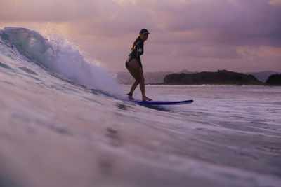 Young woman surfing at sunset