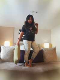 Full length portrait of happy woman sitting on sofa at home