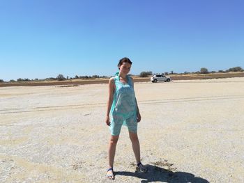 Full length of mature woman standing on field against clear blue sky during sunny day