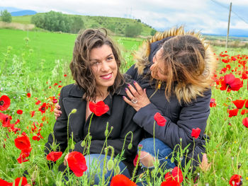 Women around poppy flowers on field