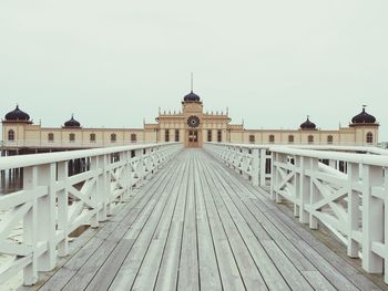 Footbridge leading towards bathhouse against sky