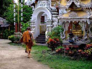 Rear view of woman walking in temple against building