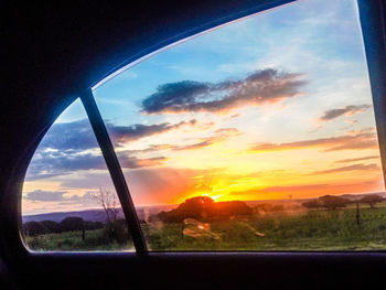 Scenic view of landscape seen through window during sunset