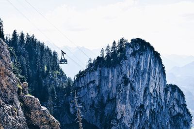 Low angle view of overhead cable car by mountain against sky