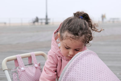 Young girl playing with her toy stroller on the boardwalk