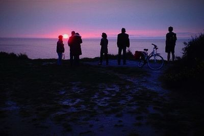 Silhouette of people on beach at sunset