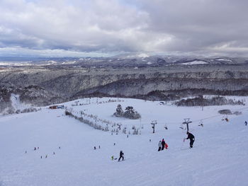 Group of people on snowcapped mountain against sky