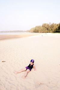 Young woman on beach against clear sky