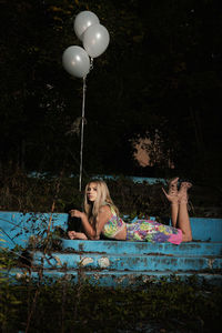 Low section of two women sitting on balloons