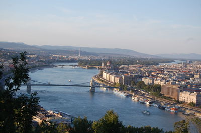 Bridge over river in city against sky