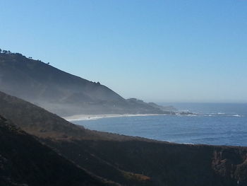 Scenic view of sea and mountains against clear blue sky