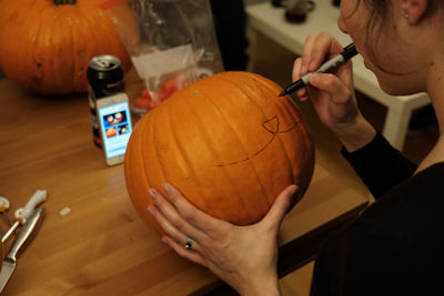 Close-up of hand holding pumpkin at table