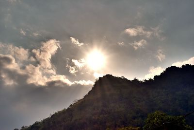 Low angle view of sunlight streaming through mountain against sky