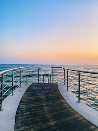 Pier over sea against clear sky during sunset