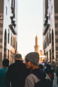 Rear view of men standing on street in city