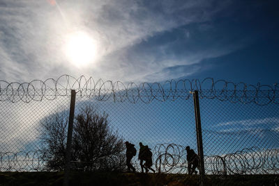 Barbed wire fence against clear sky at sunset