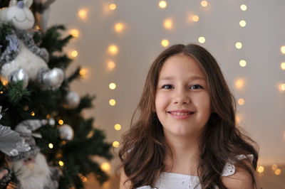 Portrait of young woman against christmas tree