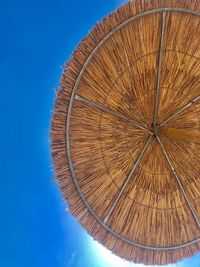 Low angle view of parasol against clear blue sky