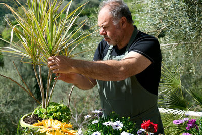 Full length of man working on flowering plant