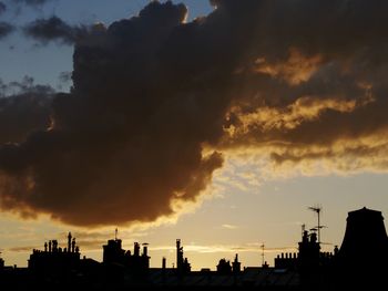 Silhouette buildings against dramatic sky during sunset