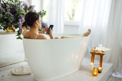 Rear view of woman with dog in bathroom