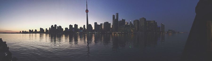 River in front of city against clear sky at dusk