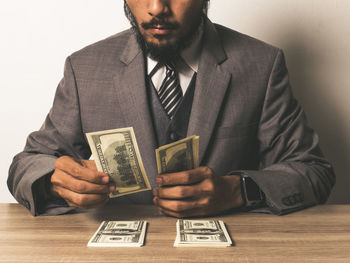 Midsection of businessman with paper currency at table