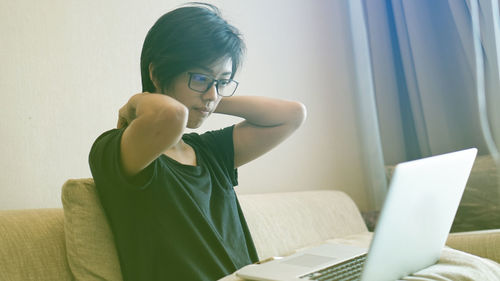 Woman using laptop while sitting on sofa at home