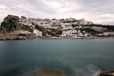 Buildings by sea against sky